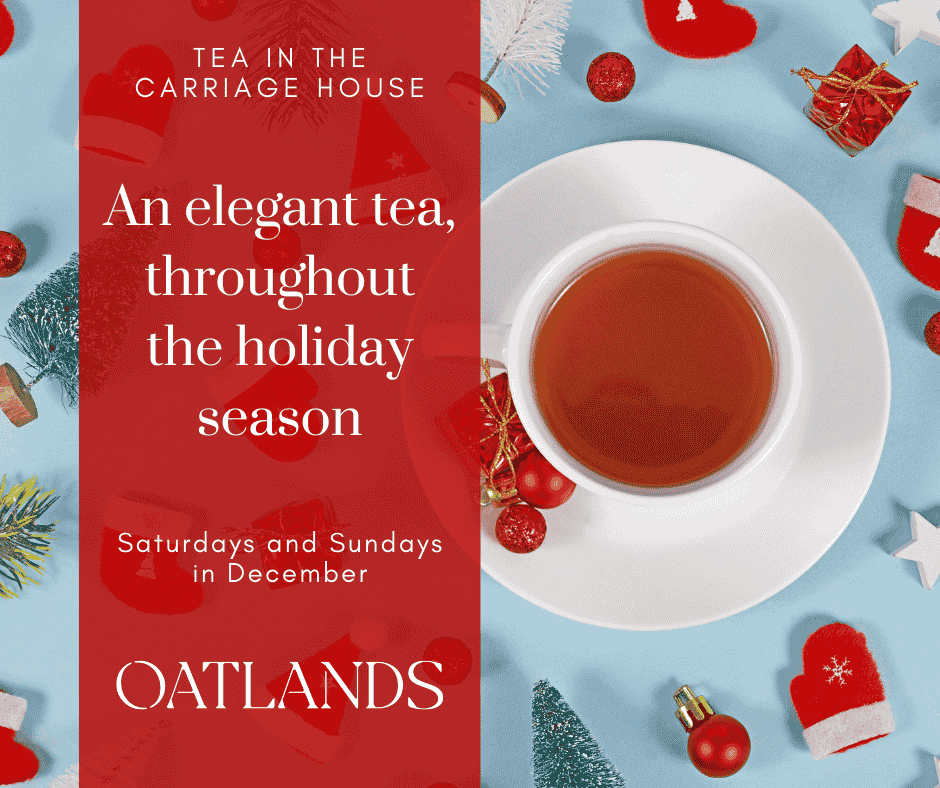 White tea cup and saucer sitting on an icy blue tablecloth with red and green tiny ornaments place all around the table.