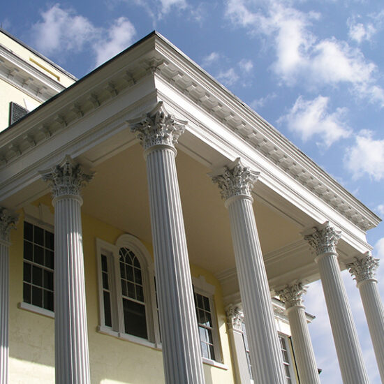 Photo looking up at an angle at the portico and columns of the mansion.